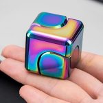 Cubo fidget com acabamento iridescente, detalhes de canto e superfície brilhante, visto de cima na mão de uma pessoa.