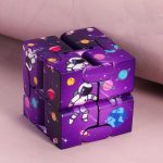 Cubo Infinito com ilustrações de astronauta, planetas e estrelas em fundo roxo, com várias faces visíveis, destacando detalhes do design espacial.
