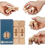 Vários cubos de madeira com engrenagens e peças de encaixe, mãos manipulando o brinquedo, caixa azul ao lado, foco na interação e detalhes do produto.