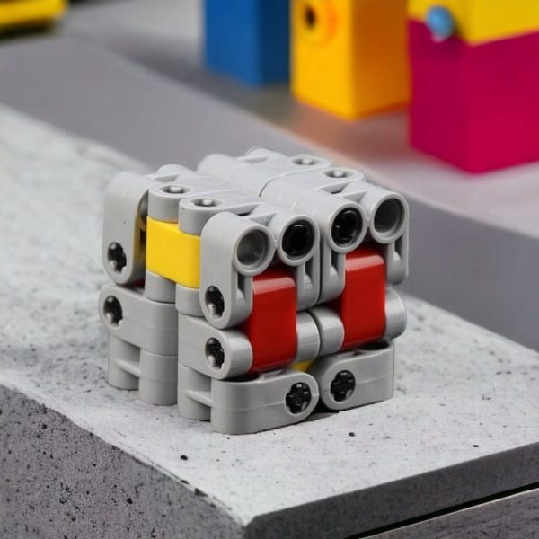 Cubo Infinito LEGO com peças cinzentas, vermelhas e amarelas, visto de cima, com detalhes das conexões e encaixes.