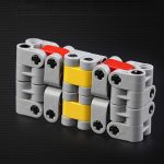 Peças de LEGO cinzentas, amarelas e vermelhas formando um cubo infinito, vista de perto com detalhes das ligações.