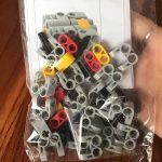 Peças de LEGO em várias cores e tamanhos, incluindo peças cinzentas, vermelhas, amarelas e pretas, usadas para construir o Cubo Infinito.