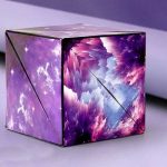 Cubo de origami com padrão de galáxia, cores roxas, azuis e brancas, com efeito de nuvens e estrelas, visto de vários ângulos.