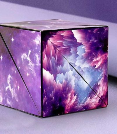 Cubo de origami com padrão de galáxia, cores roxas, azuis e brancas, com efeito de nuvens e estrelas, visto de vários ângulos.