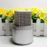 Cubo de 1000 esferas magnéticas de 5 mm, com acabamento metálico brilhante, colocado sobre uma base de metal, com fundo de flores amarelas e verdes.
