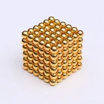 Cubo de bolas magnéticas douradas, mostrando detalhes de várias faces e a sua estrutura tridimensional.