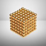 Cubo magnético dourado composto por bolas de 3mm, formando uma estrutura tridimensional de 6x6x6 unidades, com acabamento brilhante e superfície lisa.
