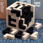 Cubo de madeira com peças pretas e naturais, algumas fora do cubo, mostrando o seu encaixe e design.