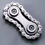 Corrente de bicicleta de metal com rolamentos visíveis, focada na ligação entre os elos e os rolamentos.