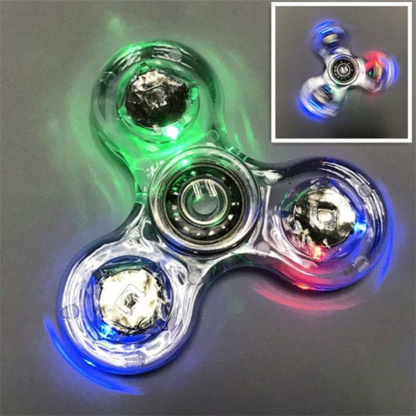 Fidget spinner luminoso com três braços, cada um com LEDs verdes, azuis e vermelhos, em movimento rápido, criando efeito de luzes brilhantes e cores vibrantes.