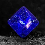 Cristal de plasma azul com superfície brilhante e detalhes internos visíveis, colocado sobre uma base escura, destacando-se pelo seu brilho intenso e cores vibrantes.