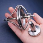 Giroscópio de metal com estrutura de suporte, eixo rotativo e base, segurado por uma mão, demonstrando o funcionamento do dispositivo.