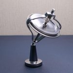 Giroscópio anti gravidade com estrutura metálica, base sólida e disco giratório em movimento, demonstrando princípios de física e estabilidade.
