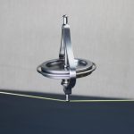 Giroscópio de metal com estrutura circular e braço de suporte, demonstrando estabilidade em movimento, com fio de teste visível na imagem.