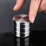 Giroscópio anti-stress de metal com várias camadas, sendo manipulado por uma pessoa com o dedo indicador.