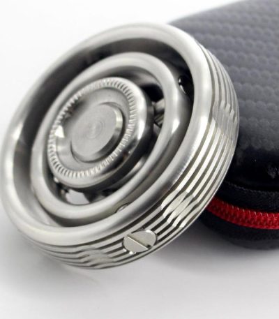 Giroscópio Fidget Spinner com acabamento metálico, detalhes circulares e mecanismo de rotação visível, junto de estojo preto com fecho vermelho.