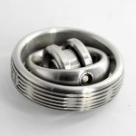 Giroscópio Fidget Spinner de metal com engrenagens visíveis e design circular, mostrado de cima com detalhes de acabamento metálico brilhante.