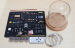 Conjunto de componentes eletrónicos, cabos, relés, e um vidro de exibição de grande dimensão, dispostos sobre uma superfície de madeira clara.