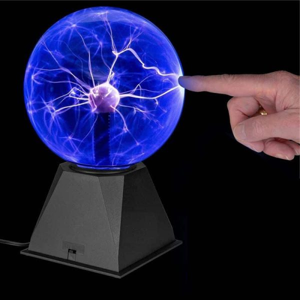 Pessoa a tocar na esfera de plasma azul, que mostra descargas elétricas visíveis e brilhantes, sobre base preta, com fundo escuro.