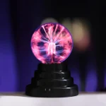 Lâmpada de plasma USB de 15 cm com faíscas de energia visíveis dentro de uma esfera de vidro, sobre base preta, com efeito de luzes coloridas e brilho intenso.