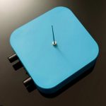Relógio de mesa azul com ponteiro único e botões laterais pretos, vista superior.