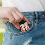 Dado de quebra-cabeça branco com detalhes vermelhos, parcialmente escondido no bolso de calças jeans.