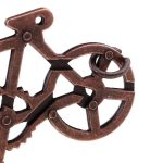 Peça de puzzle de metal com detalhes de roda, quadro e guidão de bicicleta, vista de perto.