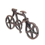 Peça de puzzle metálica em forma de bicicleta com detalhes de engrenagens e rodas, vista de ângulo ligeiramente superior.