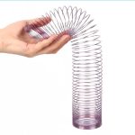 Mola Slinky de vidro transparente sendo esticada por uma mão, mostrando a sua elasticidade e forma em espiral.