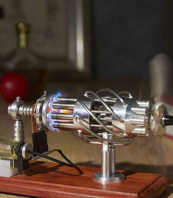 Motor Stirling metálico com tubos de calor, componentes de metal brilhante, em funcionamento, com chama visível na câmara de combustão, montado numa base de madeira.