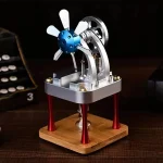 Pequeno motor Stirling com hélice de metal, estrutura metálica e base de madeira, em destaque numa superfície de madeira escura.