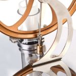 Detalhe do motor Stirling com componentes metálicos e estrutura de madeira, mostrando o pistão e o disco de movimento.