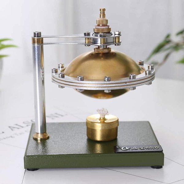 Motor Stirling com componentes metálicos dourados e prateados, base verde escura, mostrando o funcionamento com vapor de água.