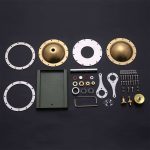 Conjunto de componentes metálicos e peças de montagem para motor Stirling, incluindo discos, parafusos, porcas, ferramentas e caixa de armazenamento.