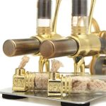 Motor Stirling com componentes de metal dourado, tubos de vidro e fios de algodão, mostrando detalhes do funcionamento interno e estrutura.