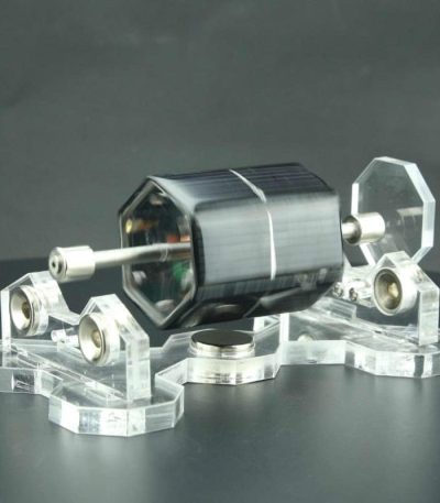 Motor Stirling solar com componentes de vidro e metal, apoiado em base de acrílico transparente, com foco na estrutura e detalhes do funcionamento.