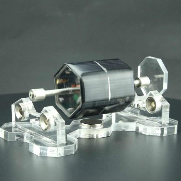 Motor Stirling solar com componentes de vidro e metal, apoiado em base de acrílico transparente, com foco na estrutura e detalhes do funcionamento.