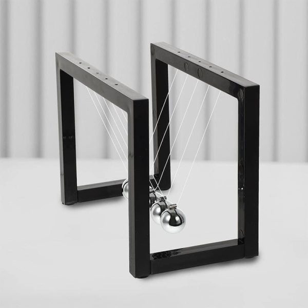 Pêndulo de Newton com moldura preta, bolas metálicas suspensas por fios finos, exibido em fundo branco com painéis de madeira.