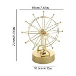 Pêndulo de Newton com esferas de metal dourado suspensas por fios finos, base redonda dourada, mostra o movimento das esferas ao balançar.