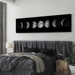 Painel decorativo com imagens das fases da lua em sequência, em tons de cinza, pendurado na parede acima da cama.