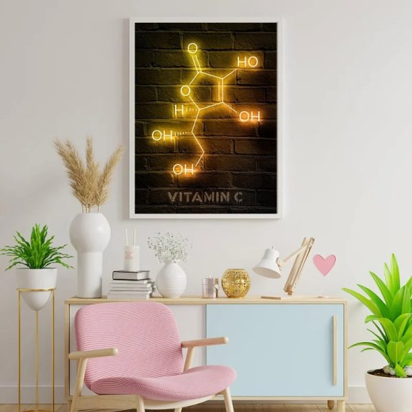 Quadro decorativo com fórmula da vitamina C em neon amarelo e laranja numa parede de tijolos escuros, em ambiente de sala moderna com mobília clara e plantas.