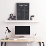 Quadro de Código Morse com letras e números, decorativo na parede de um escritório moderno, ao lado de uma planta e uma ampulheta.