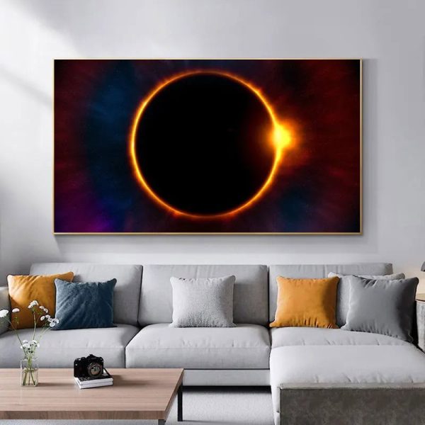 Fotografia de um eclipse solar com anel de fogo, exibido numa tela grande numa sala moderna com sofá e almofadas coloridas.