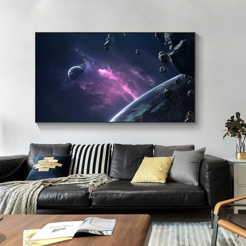 Painel decorativo com imagem de espaço, asteroides e planeta, em cores vibrantes de roxo e azul, pendurado na parede de sala moderna.