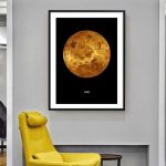 Fotografia de um poster do planeta Vénus com detalhes da sua superfície, em moldura preta numa parede branca, com uma cadeira amarela ao lado.