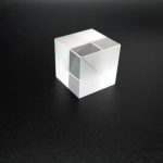 Cubo de dispersão óptica transparente com faces planas e acabamento brilhante, usado para demonstrações de dispersão de luz.
