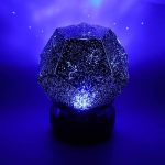 Projetor de constelações em forma de dodecaedro com luzes LED que projeta estrelas e constelações no teto, ideal para decoração educativa e científica.