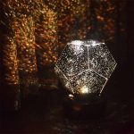 Projetor de estrelas com forma de dodecaedro, emitindo luz brilhante e projeções de estrelas no teto escuro, ideal para decoração de ciência.