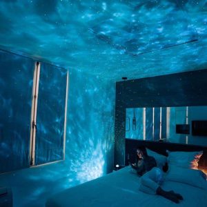 Projeção de estrelas e constelações no teto de um quarto escuro, criando efeito de céu noturno.