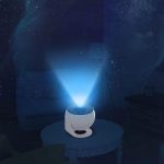 Projetor de galáxia em funcionamento, projetando estrelas e nebulosas no teto escuro, com luz azul e branco, em ambiente de sala de estar.